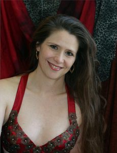 headshot of dancer with long brown hair in red halter top in front of a red curtain